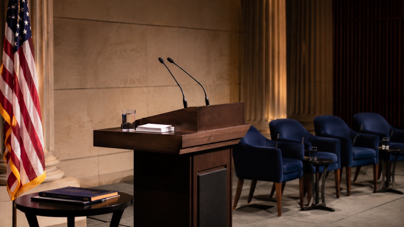Empty speaker podium with American flag and a row of blue chairs awaiting faculty
