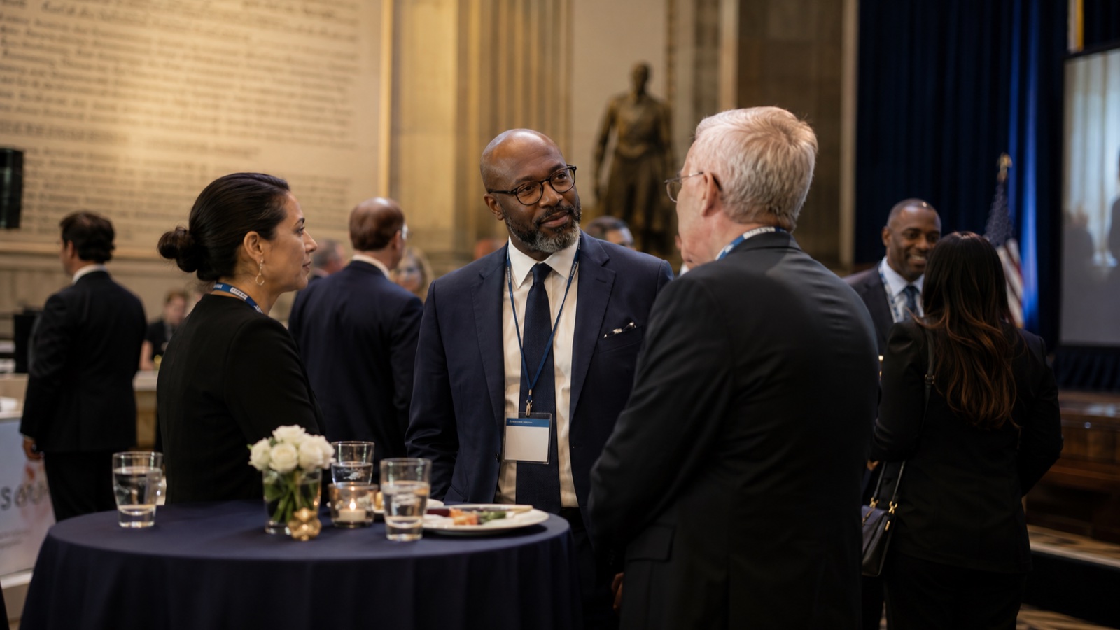 Networking reception at the Summit — attendees mingling with drinks at small tables in a venue with classical architecture